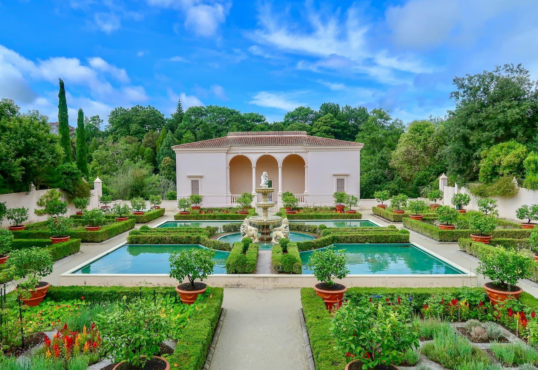 Formal gardens and a fountain in Hamilton Gardens under a blue sky