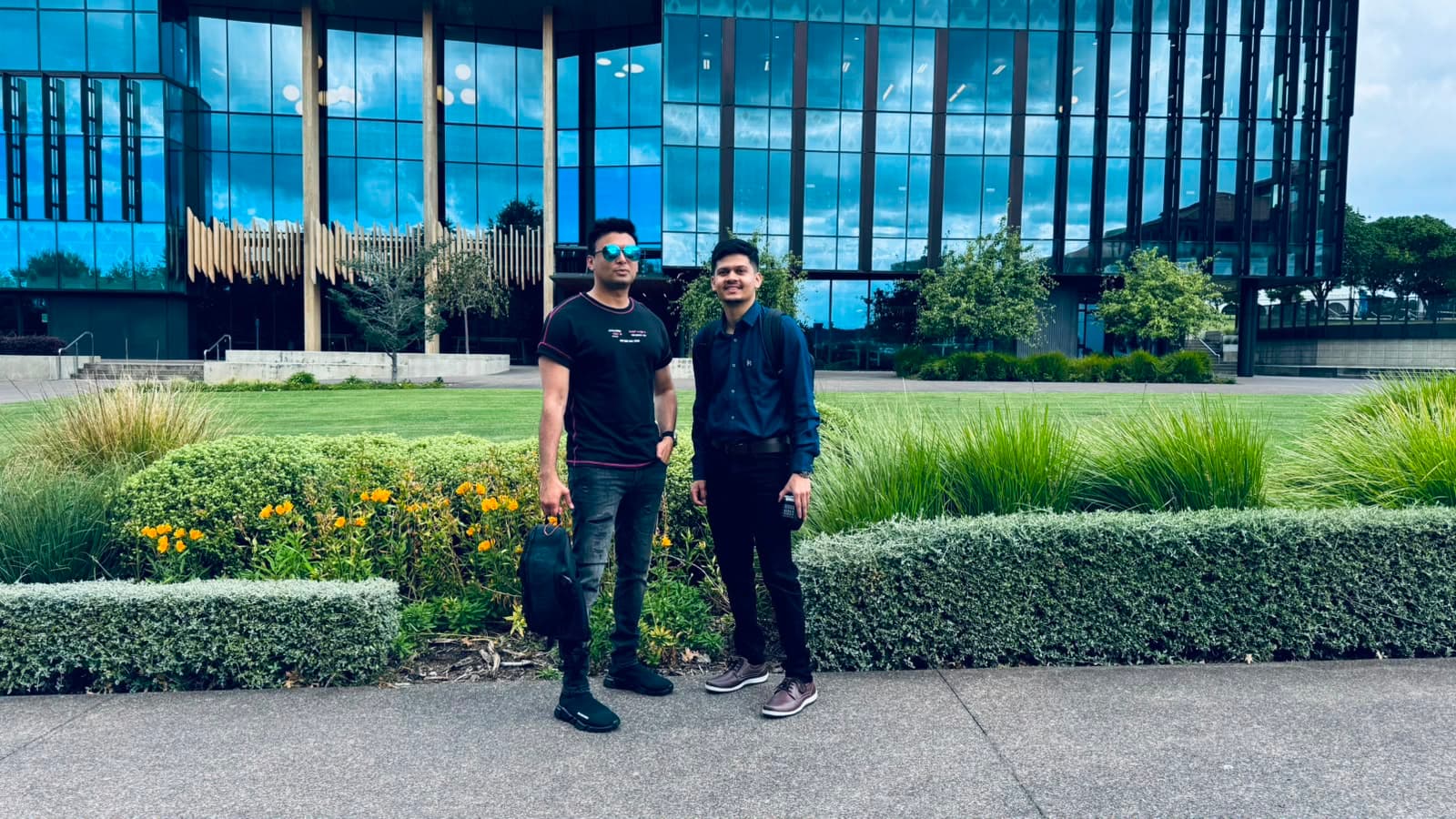 Two visitors standing in front of a modern glass building