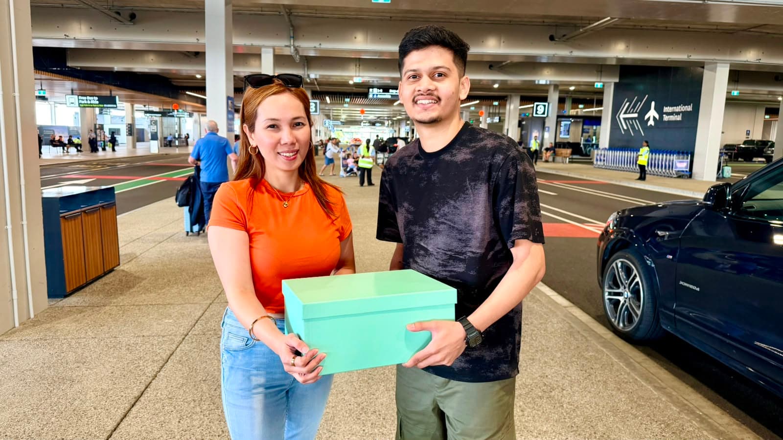 Two people at an international airport, sharing a welcome gift