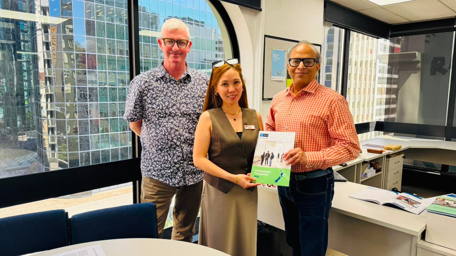 Three people meeting with an international study prospectus