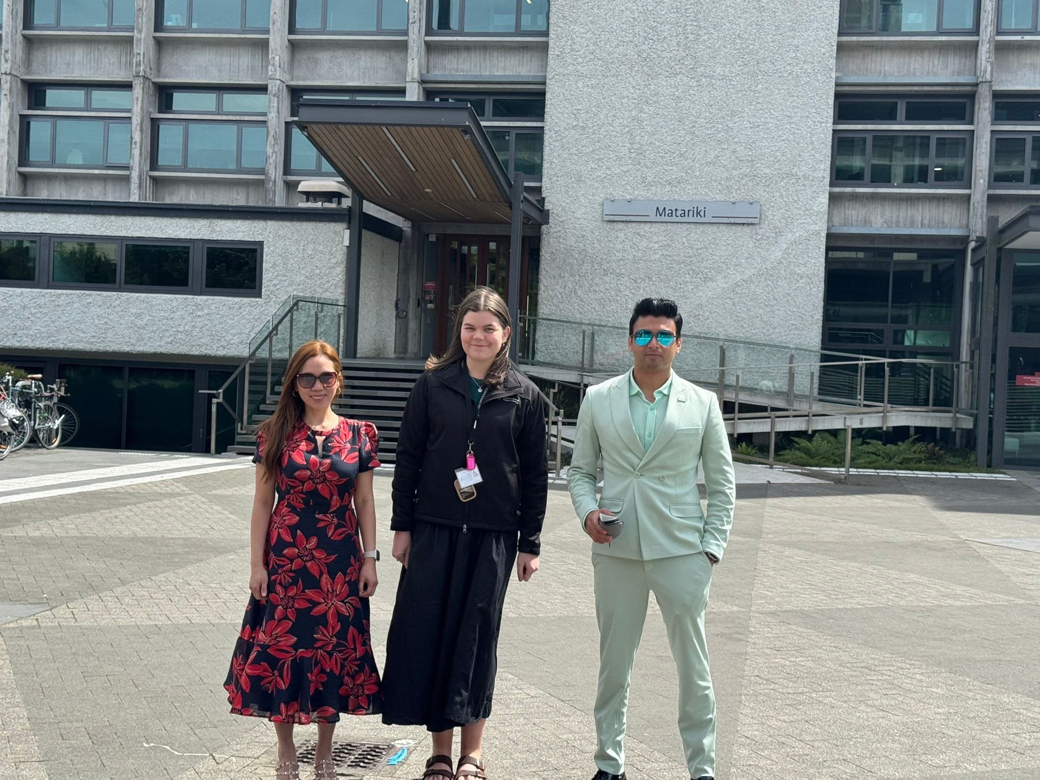 Three visitors standing outside the Matariki building on campus